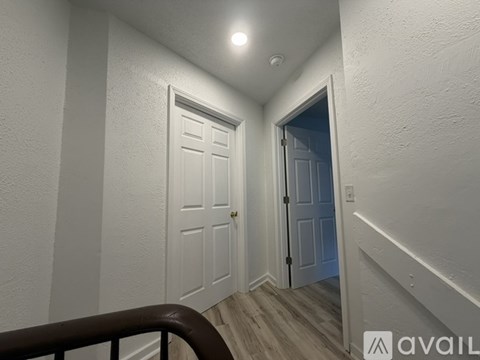 A hallway with a white door and a brown railing.