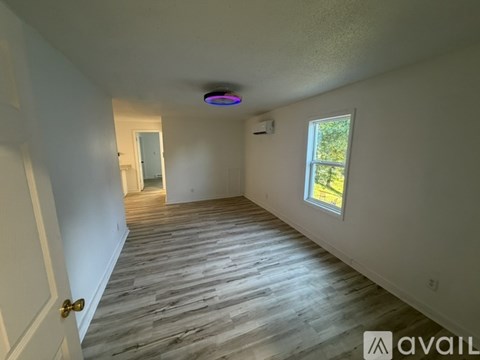 A room with a wooden floor and a window on the right side.