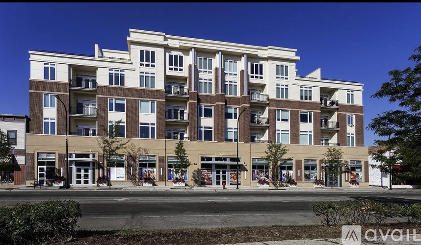 A large apartment building with multiple balconies and a clear blue sky above.