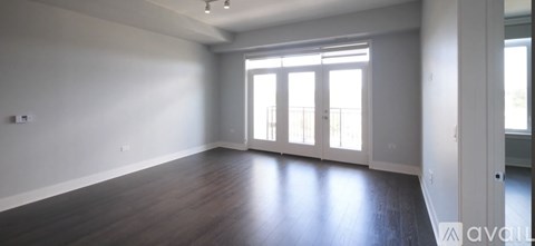 A spacious room with wooden floors and a large window.
