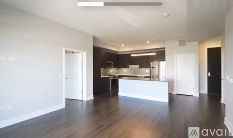 A spacious, well-lit room with a kitchen area in the background.
