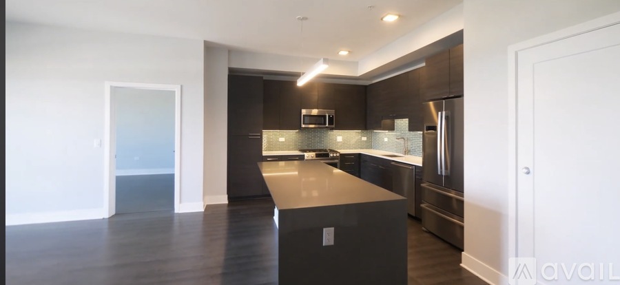 A modern kitchen with dark wood floors and stainless steel appliances.