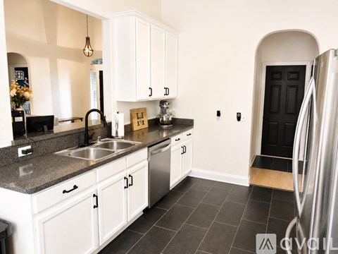A kitchen with white cabinets and a black door.
