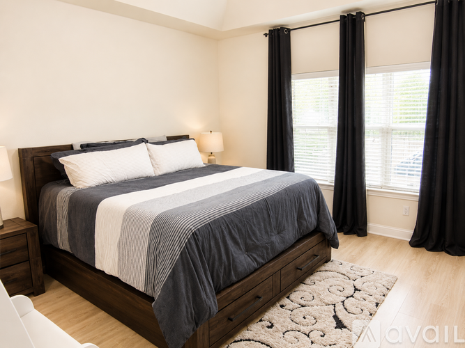 A bedroom with a large bed and a window with black curtains.
