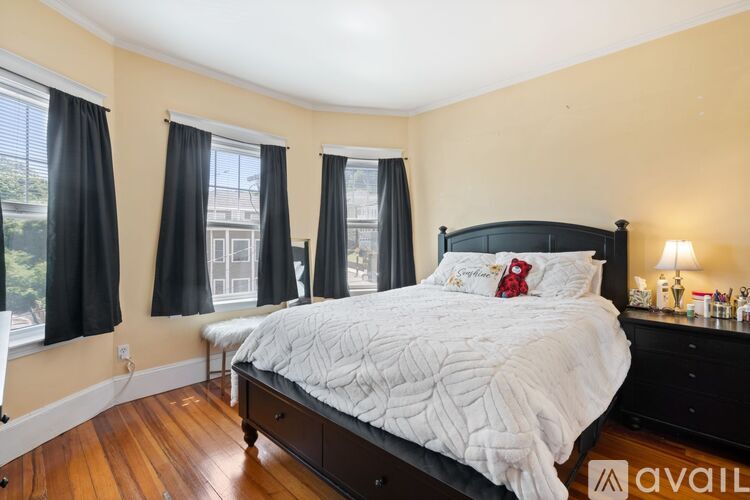 A bedroom with a large bed and a window with black curtains.