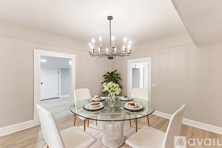 A dining room with a glass table and white chairs.