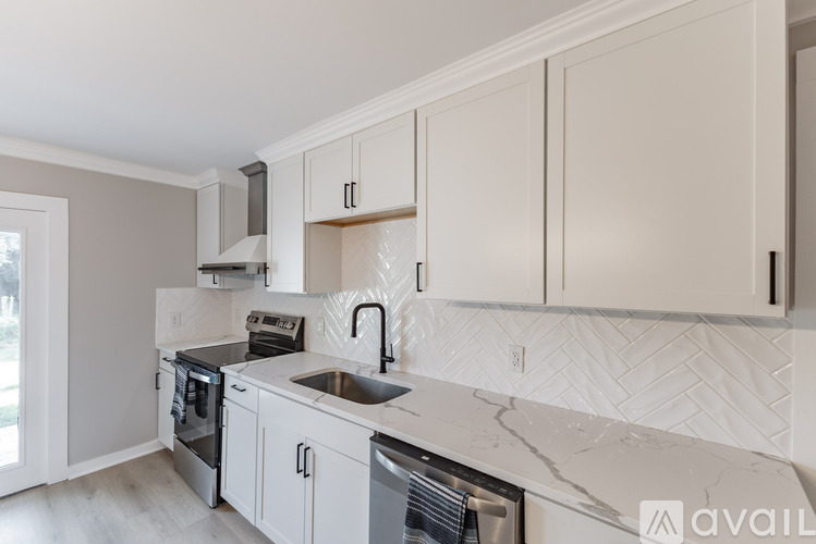 A kitchen with white cabinets and a marble countertop.