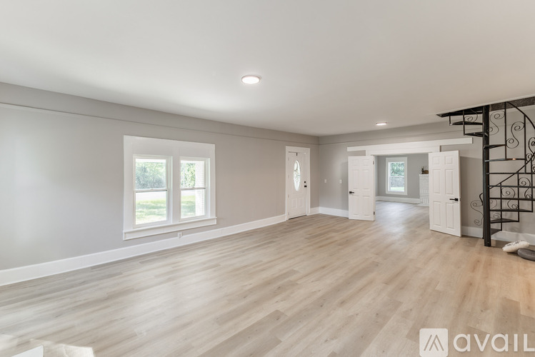 A spacious room with wooden flooring and a large window.