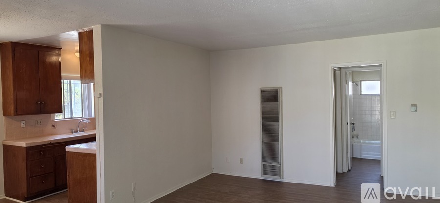 A room with a kitchen area and a doorway leading to another room.