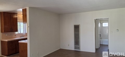 A room with a kitchen area and a doorway leading to another room.
