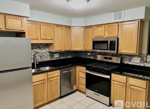A kitchen with wooden cabinets and black countertops.