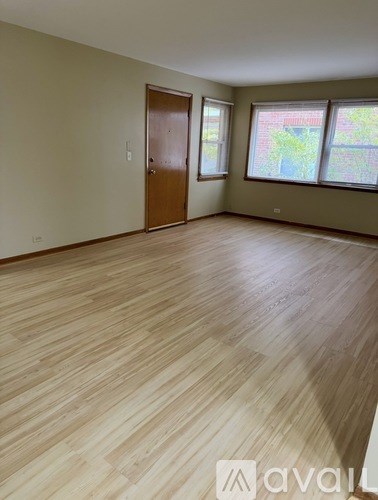 A room with wooden flooring and a window showing greenery outside.