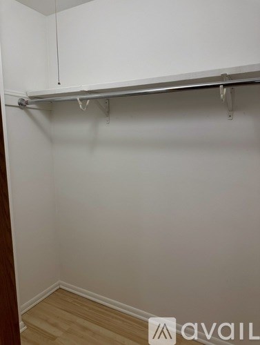 A white closet with a metal rail and hooks.