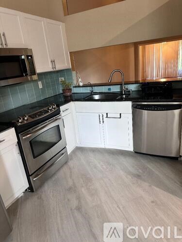 A kitchen with white cabinets and black countertops.