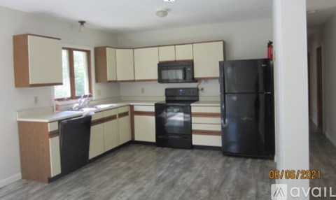 A kitchen with black appliances and wooden floors.