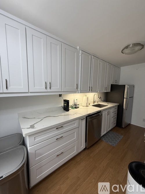 A kitchen with white cabinets and a marble countertop.