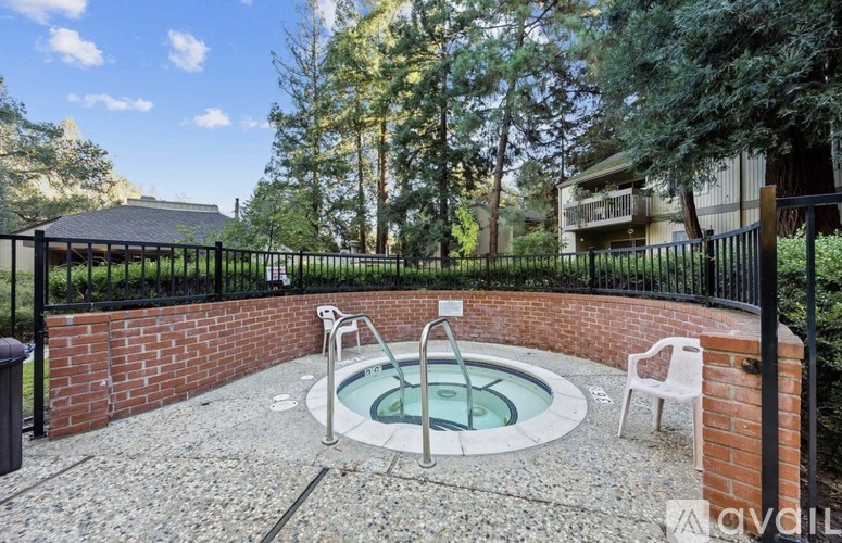 A hot tub sits in the middle of a patio surrounded by a brick wall.