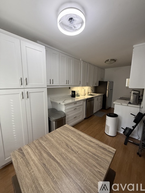 A kitchen with white cabinets and a wooden table.