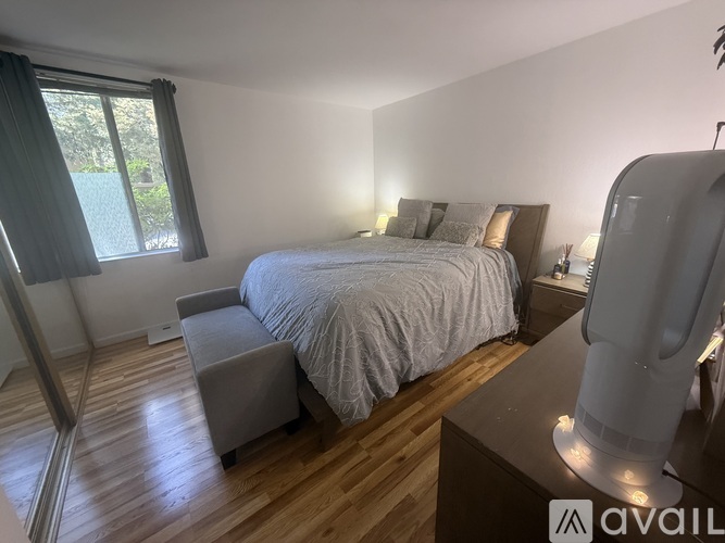 A bedroom with a bed, nightstand, and window.