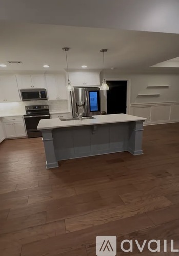A kitchen with a large island in the middle and a refrigerator with a digital display.