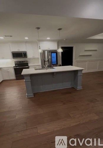 A kitchen with a large island in the middle and a refrigerator with a digital display.
