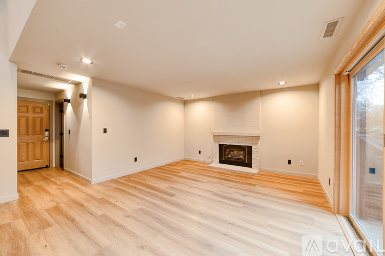 A spacious room with a fireplace and wooden flooring.