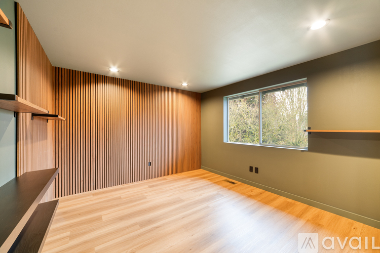 A room with wooden flooring and a window with a view of trees outside.