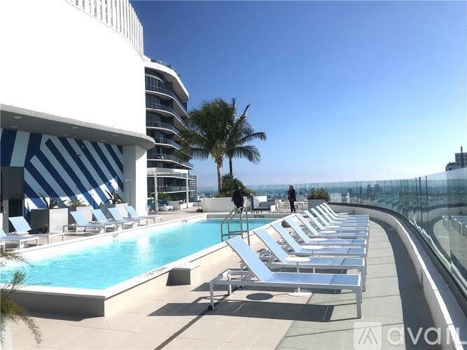 A pool with sun loungers and a person standing on the roof.