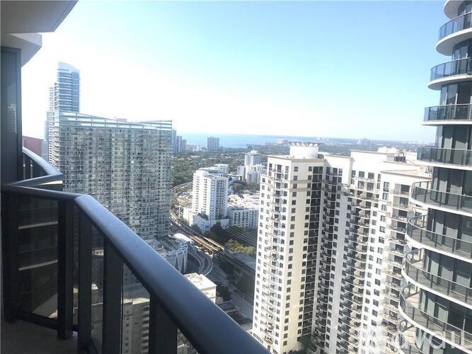 A cityscape viewed from a balcony with tall buildings.