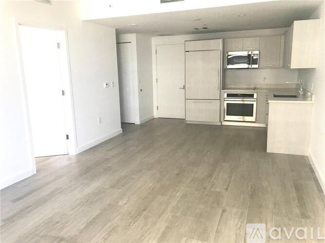 A spacious kitchen with white cabinets and a grey floor.