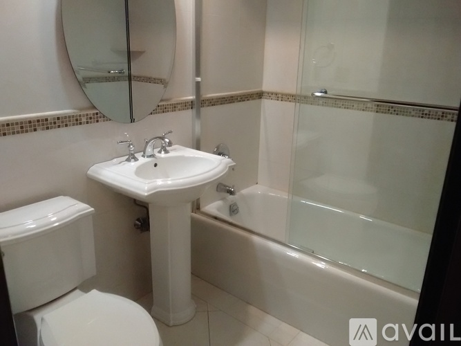 A white sink in a bathroom with a toilet and a glass shower door.