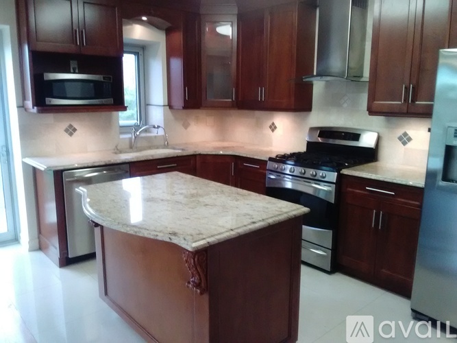 A kitchen with brown cabinets and a marble island.