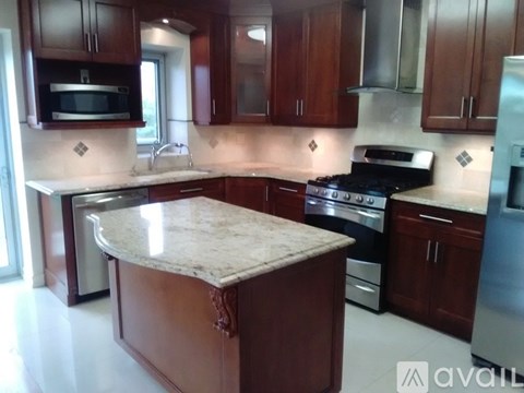 A kitchen with brown cabinets and a marble island.