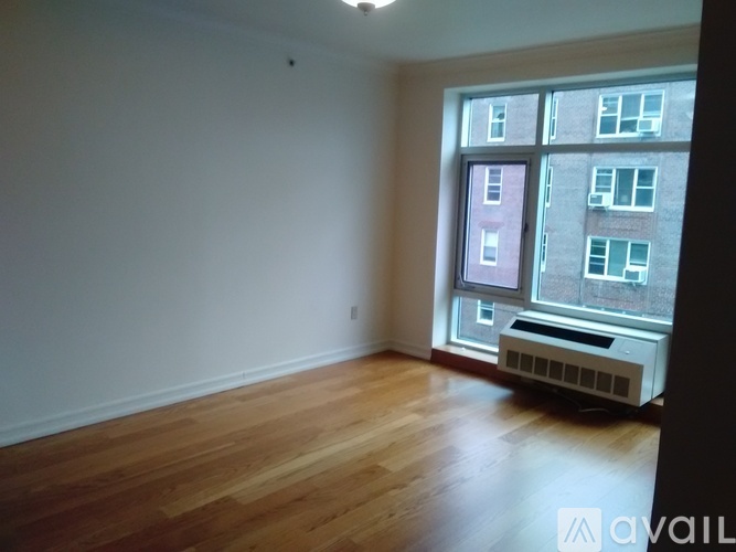 A room with wooden floors and a window overlooking a building.