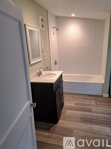A bathroom with a sink, mirror, and bathtub.