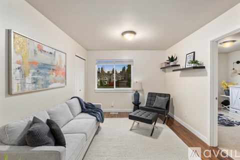 A living room with a grey couch and a painting on the wall.
