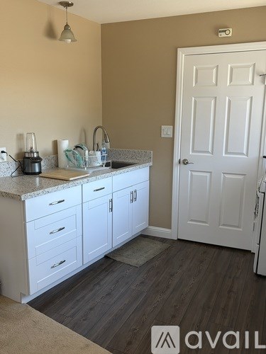 A kitchen with white cabinets and a white door.