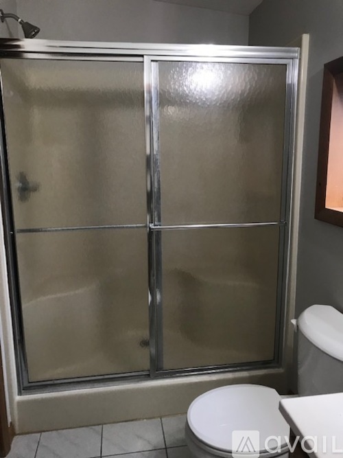 A white toilet sits next to a glass shower door in a bathroom.