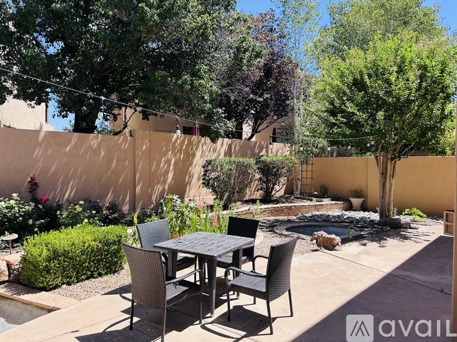 A patio with a table and chairs is surrounded by a wall and trees.