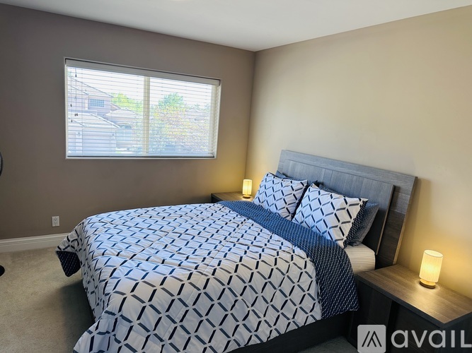 A bedroom with a bed covered in a blue and white patterned comforter.