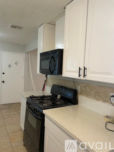 A kitchen with a black stove and white cabinets.