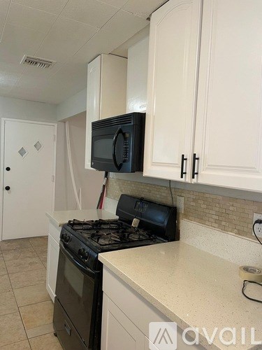 A kitchen with a black stove and white cabinets.
