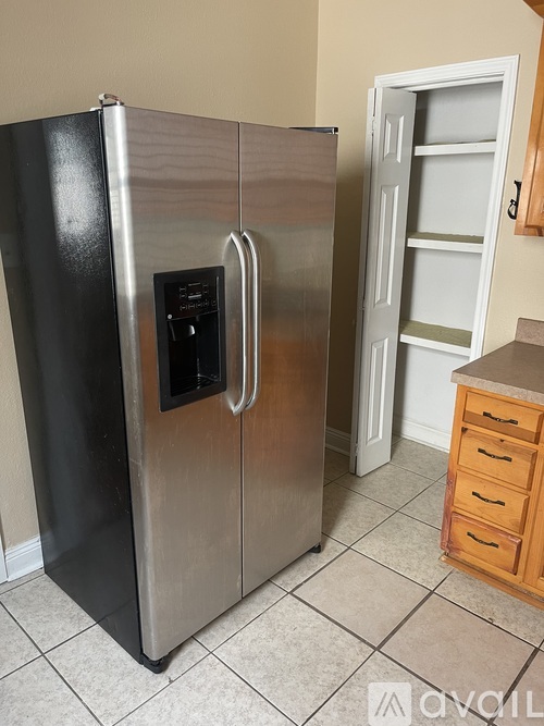 A stainless steel refrigerator with a black handle and a white door is in a kitchen.