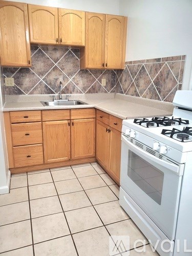 A kitchen with a white gas stove and wooden cabinets.