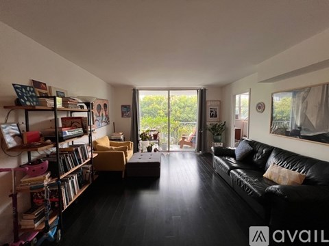 A living room with a black leather couch and a bookshelf filled with books.