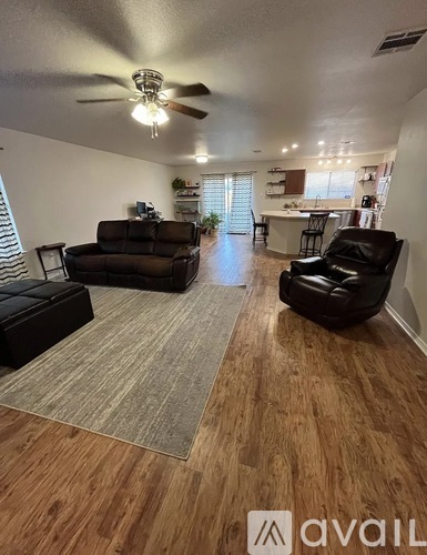A living room with a ceiling fan and two black leather chairs.
