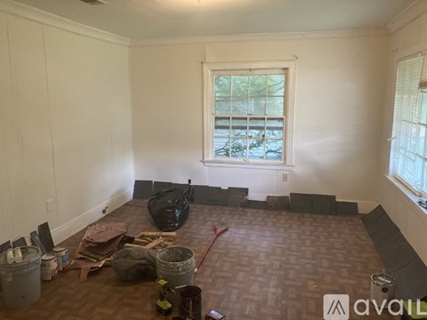 A room with a window and a brown floor is being renovated.