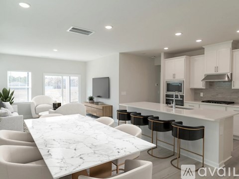 A modern kitchen with a marble table and white chairs.