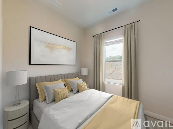 A bedroom with a large bed, a nightstand with a lamp, and a framed picture on the wall.