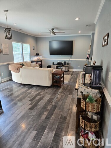 A living room with a white couch and a television on the wall.